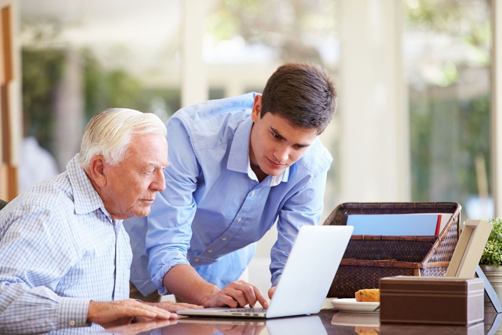 An adult learner and a professional reviewing a laptop together
